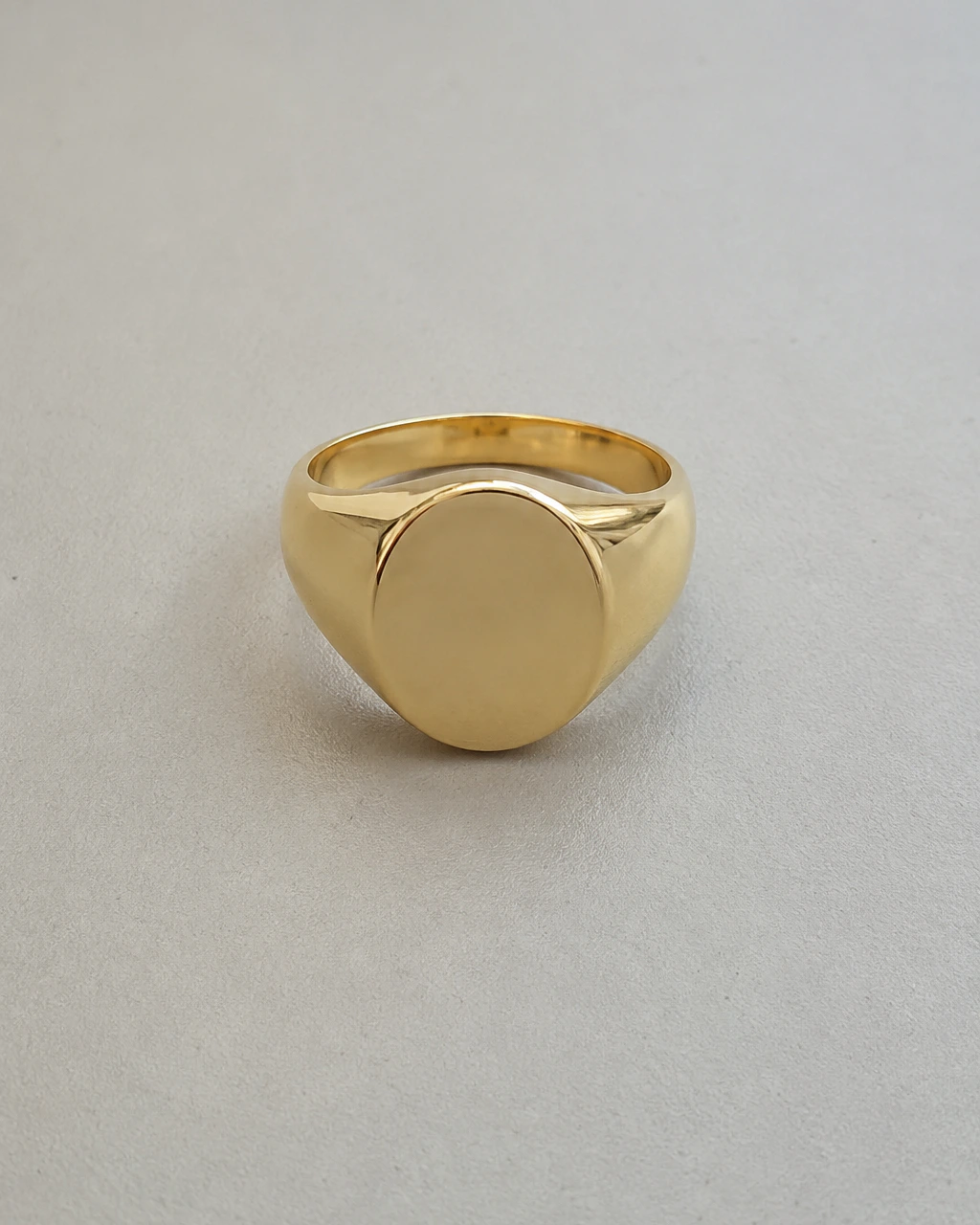 A plain smartphone photo of a gold signet ring on a desk, before any scene is generated